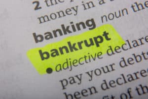 The word "bankrupt" is highlighted in a dictionary, with its definition as an adjective, "declared in law unable to pay your debts." The word "banking" is visible above it.