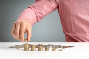 Person stacking coins on a table, representing the process of evaluating and organizing financial claims in bankruptcy cases.