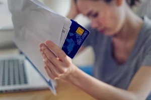 Worried person holding a credit card and financial documents, symbolizing the impact of bankruptcy on credit reports.
