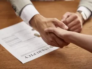 Two people shaking hands over bankruptcy documents, symbolizing relief and a fresh financial start.