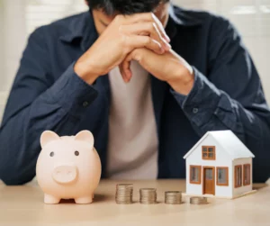 Person with piggy bank and model house illustrating how inheritance impacts bankruptcy cases in Illinois.