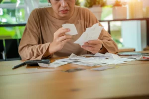 Person reviewing receipts on table illustrating self‑employed bankruptcy filing process in Illinois.